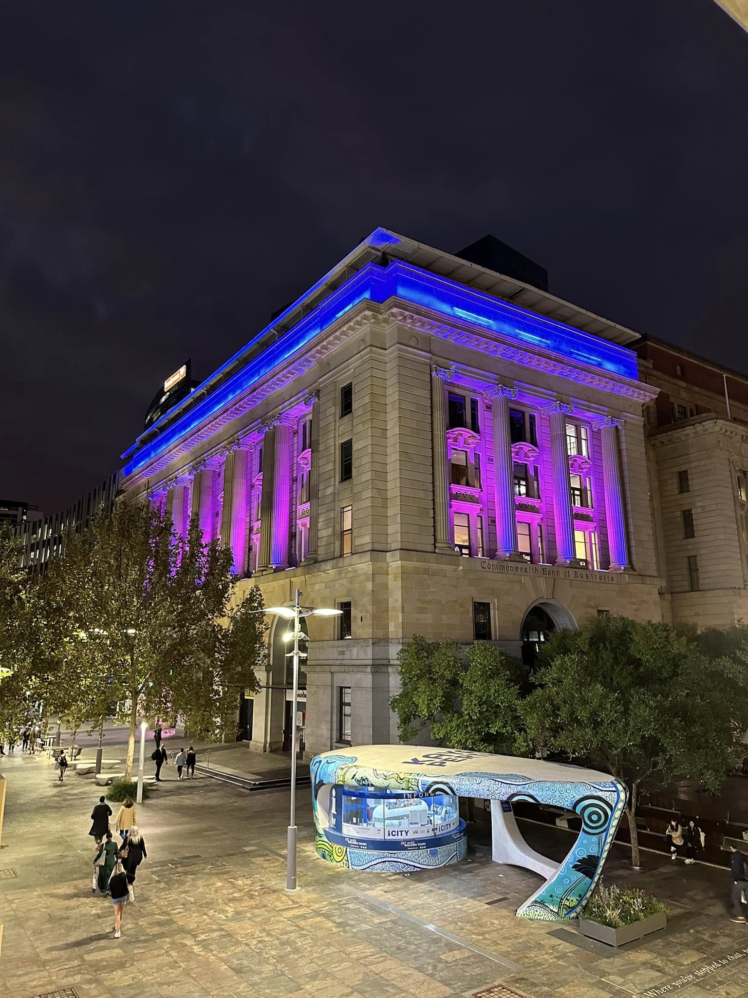 The Commonwealth Bank Building at Forrest Place lit blue and magenta at night.