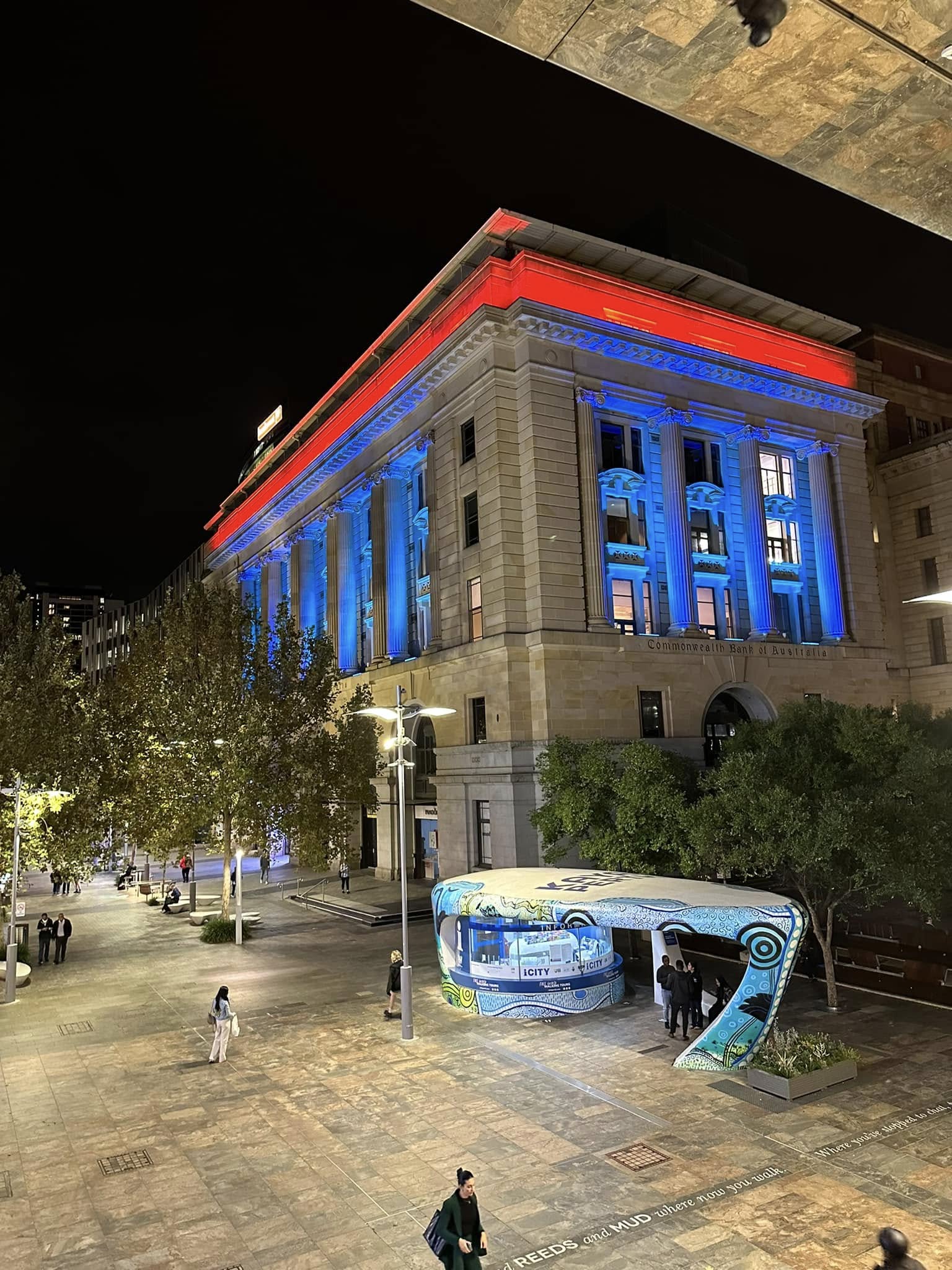 The Perth façade lit in blue and red at dusk.