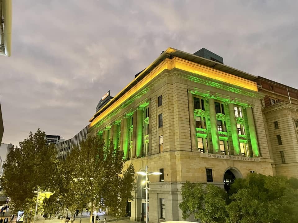 The same Perth façade lit in green and gold for a national day.