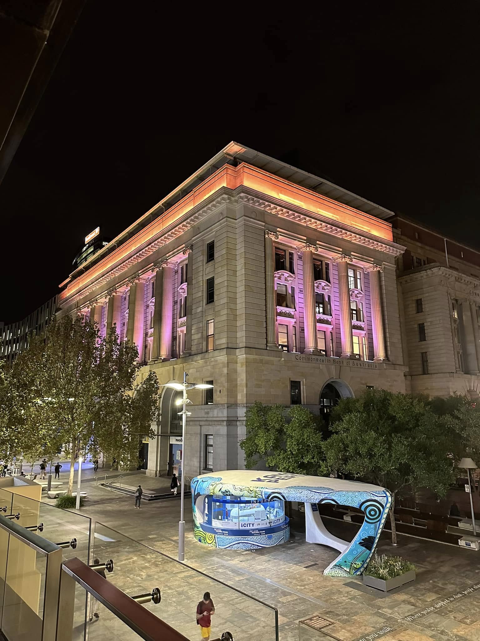 The Perth façade lit in pink and purple.