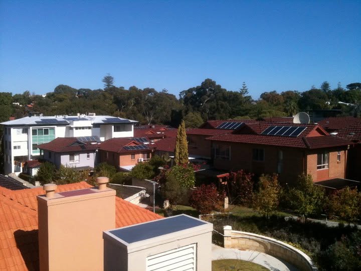 Solar array on a home with the suburb behind.