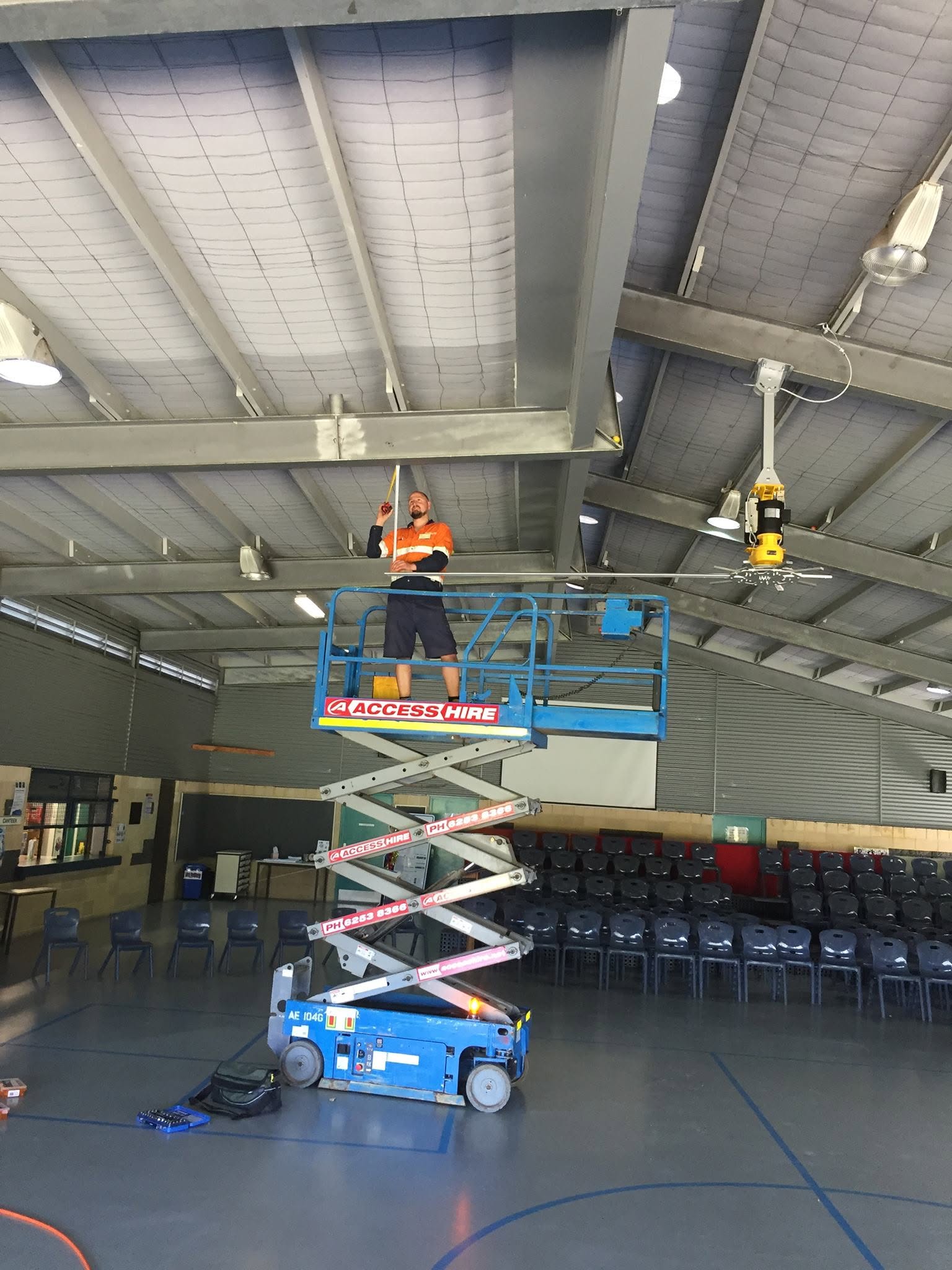 Oasis electrician on a scissor lift installing in a hall.