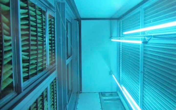 UVC lamps installed in a duct, glowing cyan.